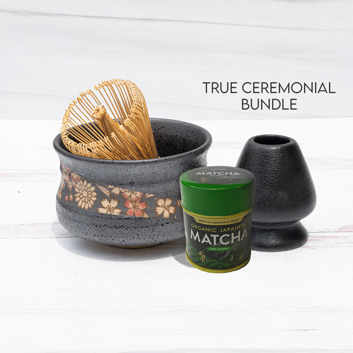 The Black with Flowers Set includes a bamboo matcha whisk, crafted using Minoyaki pottery techniques, alongside a ceramic matcha bowl, a matcha tin, and a holder, all displayed on a pristine white background.