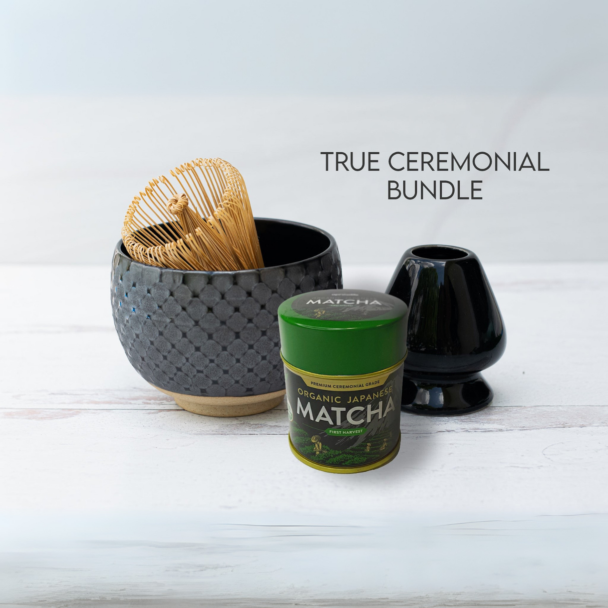 The Black Ami Pattern Set includes a ceramic matcha bowl, bamboo whisk, matcha powder tin, and black stand on a white surface. It showcases the elegance of Japanese tradition with the text "True Ceremonial Bundle.