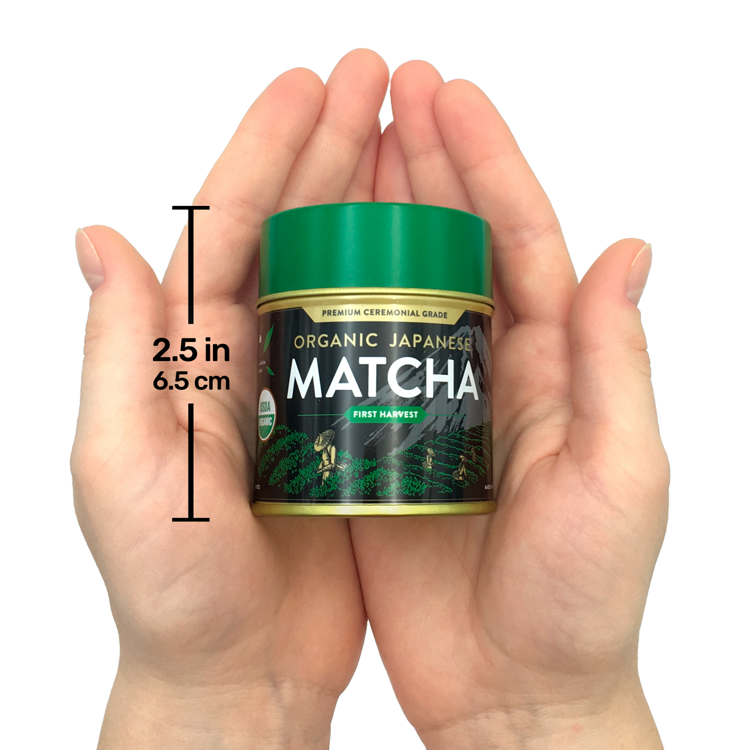 Hands holding a small tin of Organic Japanese Ceremonial Grade Matcha Green Tea Powder with a green lid, labeled "2.5 in, 6.5 cm.