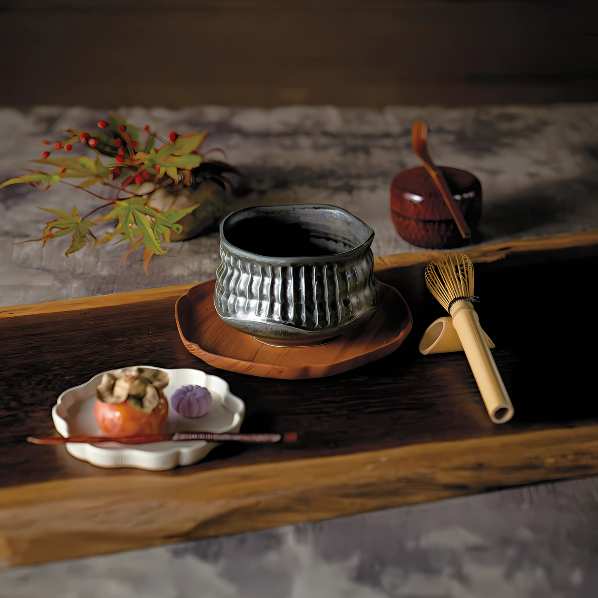 A Japanese tea ceremony setup includes a stunning Black Ceramic Meisen Matcha Bowl, a bamboo matcha whisk, a vibrant persimmon, and colorful autumn leaves carefully placed on a wooden tray.