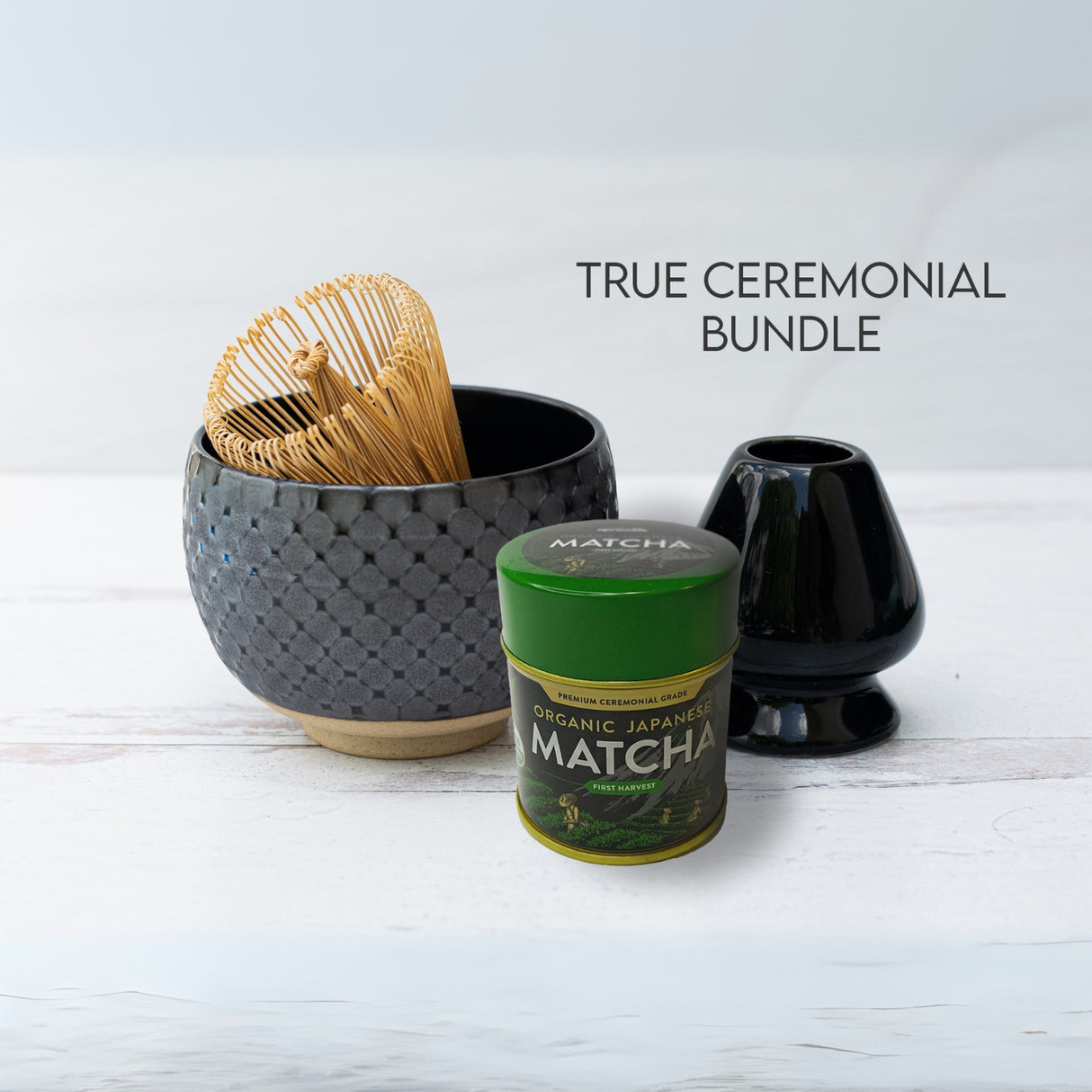 Ceremonial matcha set showcasing a Black Ami Pattern Matcha Bowl, whisk, stand, and Japanese matcha can on a pristine white surface.