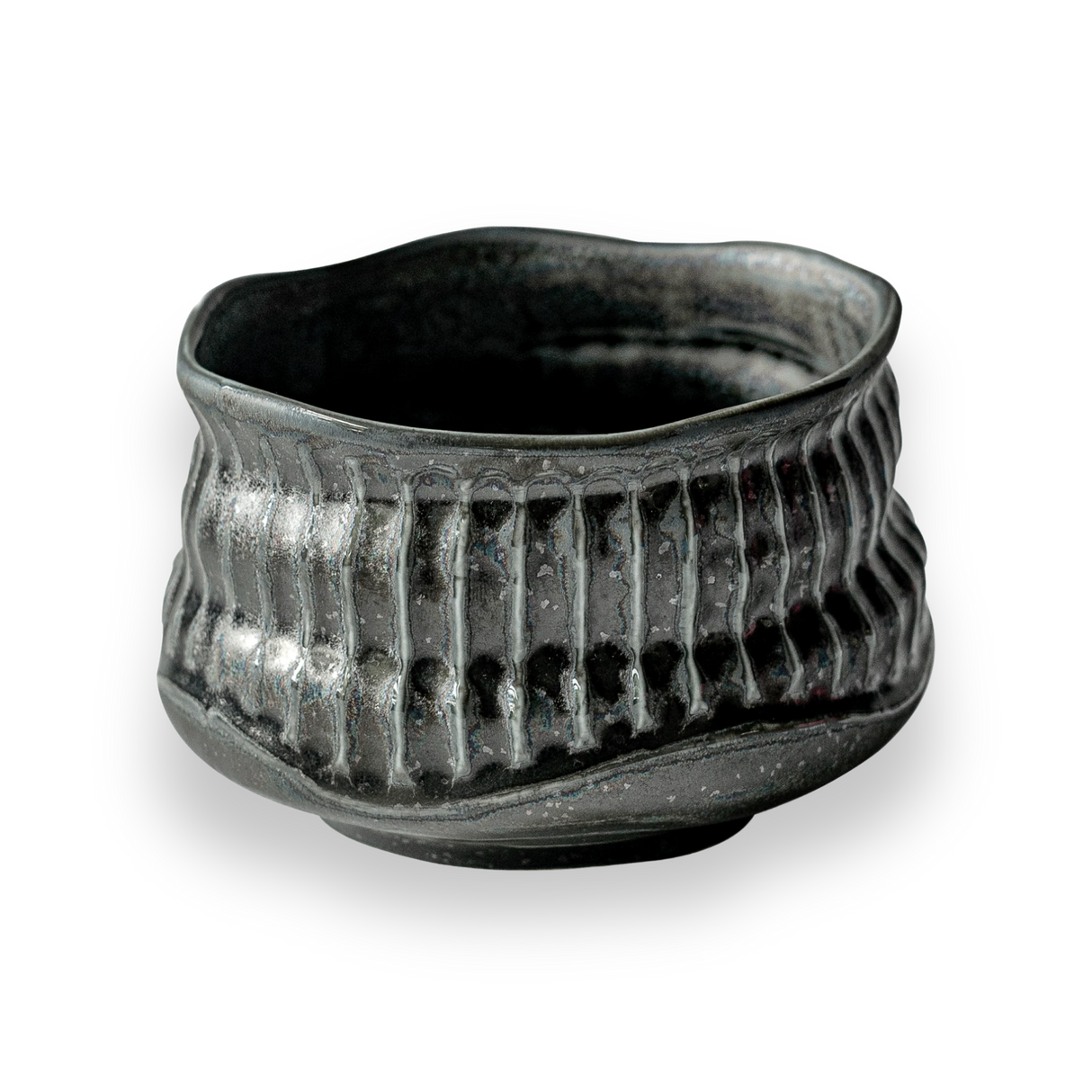 The Black Ceramic Meisen Matcha Bowl, with its textured dark finish, wavy rim, and ribbed pattern reminiscent of Minoyaki pottery, stands elegantly against a black background.