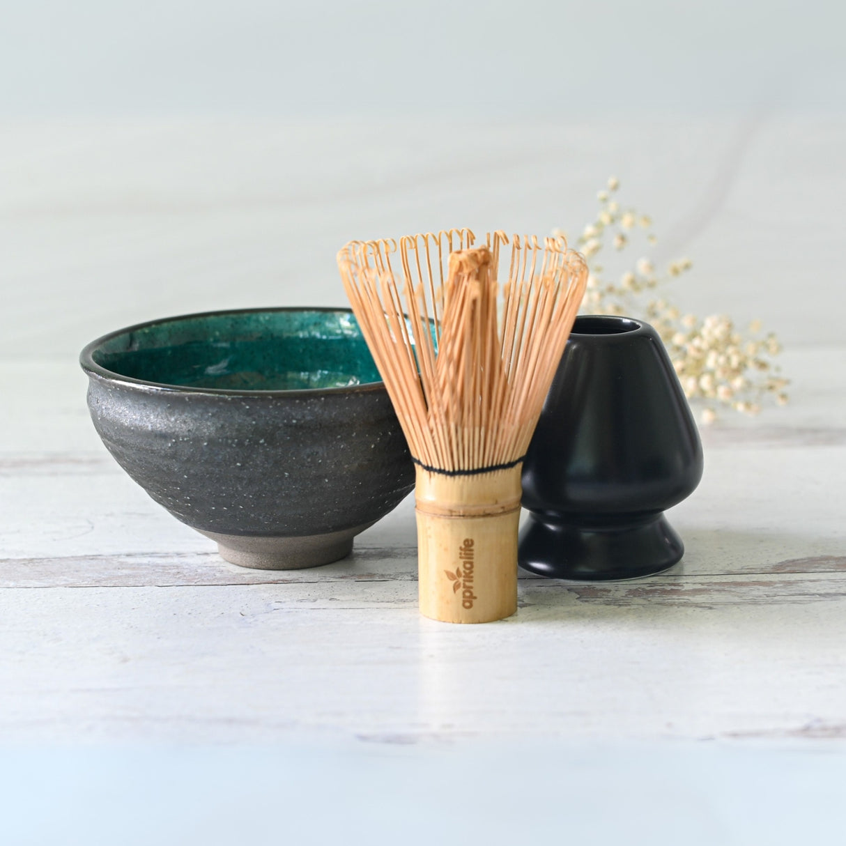 The Blue and Black Ceramic Matcha Bowl, Bamboo Matcha Whisk, Whisk Holder, and Organic Japanese Matcha Set is beautifully arranged on a light surface.