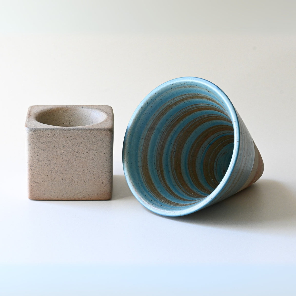 Blue Coffee Mug with Base - 6.8 oz/200ml displayed alongside a square beige vase, highlighting exquisite ceramic artistry on a neutral background.
