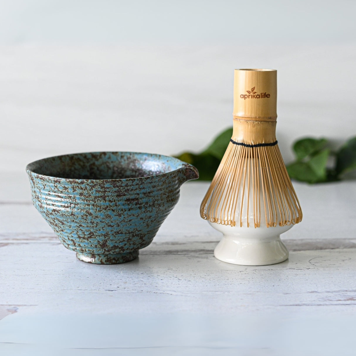 The Blue Textured Ceramic Matcha Bowl with Spout, Bamboo Matcha Whisk, and Whisk Holder Set rests on a light surface, embodying the elegance of a Japanese tea ceremony—ideal for your matcha bowl set.