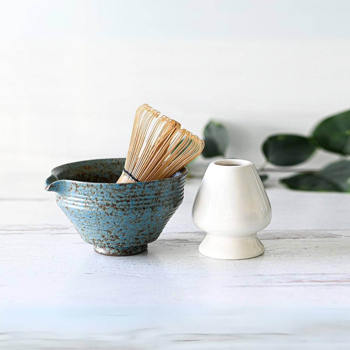 The Blue Textured Ceramic Matcha Bowl with Spout, Bamboo Matcha Whisk, and Whisk Holder Set evokes the elegance of a Japanese tea ceremony on a white surface.