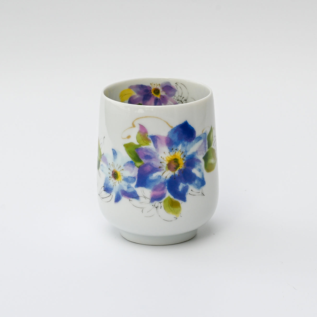 The Blue Flower Waisted Tea Cup is a white ceramic cup from our handmade drinkware collection, featuring a vibrant floral design with blue and purple flowers. Inspired by traditional Japanese pottery, it reflects the timeless elegance of Minoyaki craftsmanship.