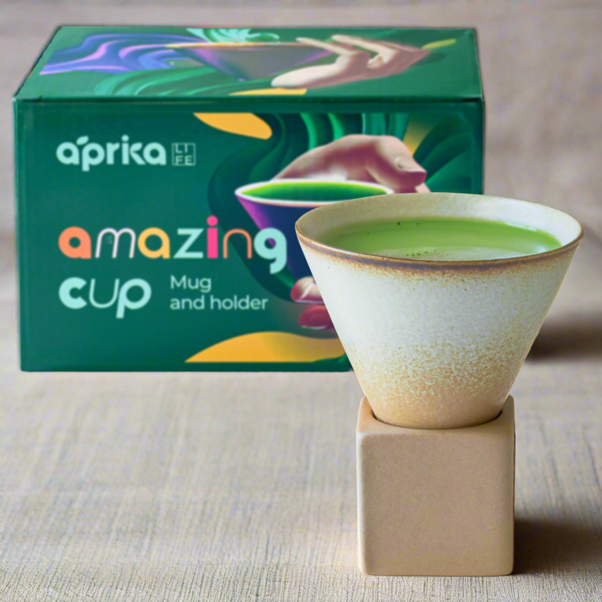 A green drink in a vintage-style brown coffee mug with a square base, featuring colorful packaging in the background.
