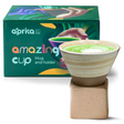 A beige coffee mug with latte gently rests on a square base amid a colorful box labeled "amazing cup." This handcrafted 6.8 oz ceramic mug is a perfect unique gift for any coffee enthusiast.