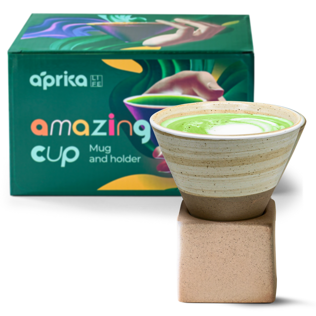 A beige coffee mug with latte gently rests on a square base amid a colorful box labeled "amazing cup." This handcrafted 6.8 oz ceramic mug is a perfect unique gift for any coffee enthusiast.