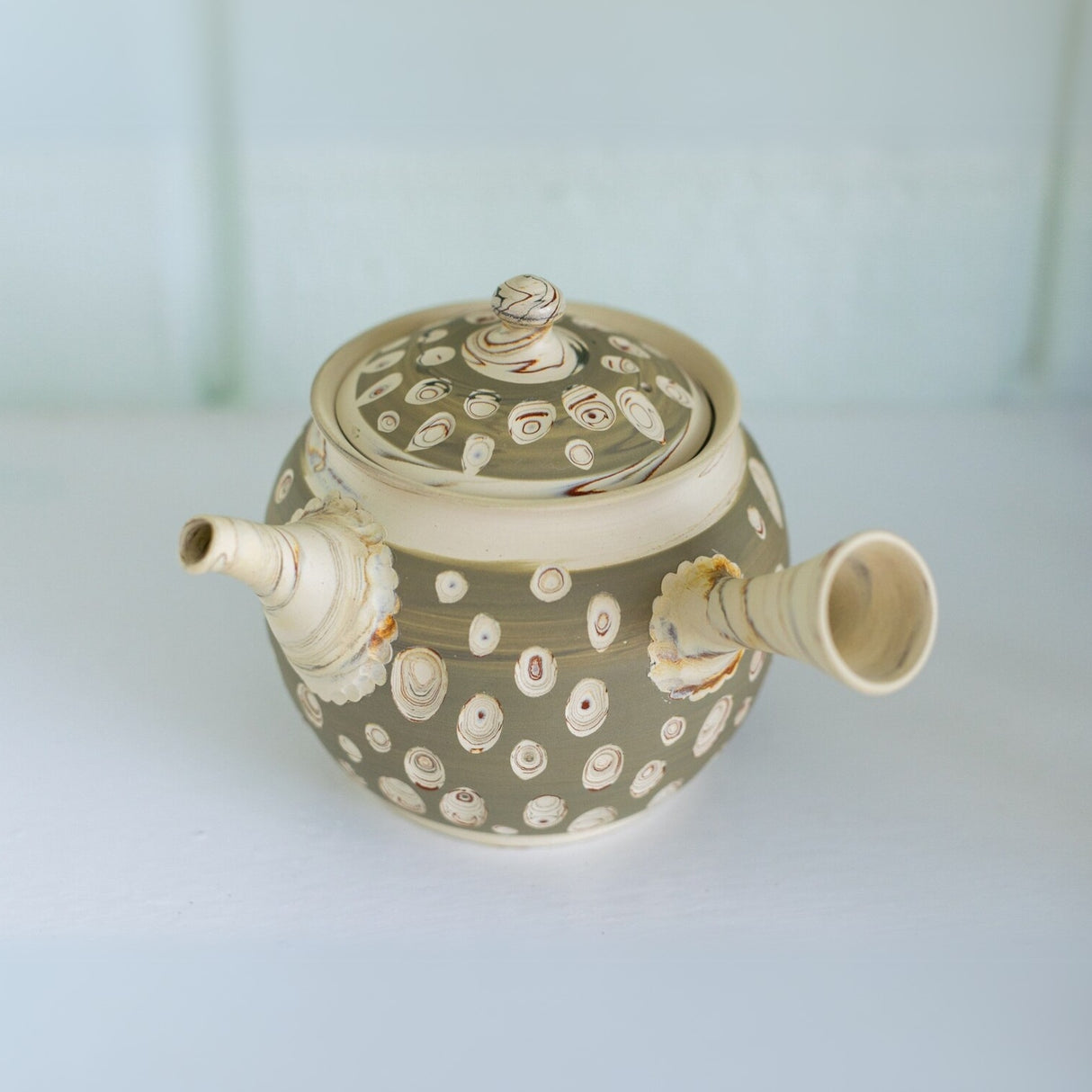 The Japanese Kyusu Set includes a teapot with filters (370ml) and two cups, crafted from Tokoname clay in beige, featuring circular patterns, a lid, and an elegantly angled spout, perfect for serving green tea.