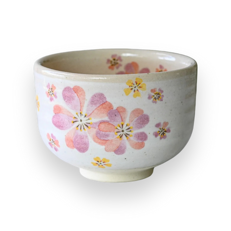 The Japanese Pink Sakura Ceramic Matcha Bowl is a white ceramic matcha bowl featuring pink and yellow flowers on a black background, crafted in the traditional Minoyaki style.