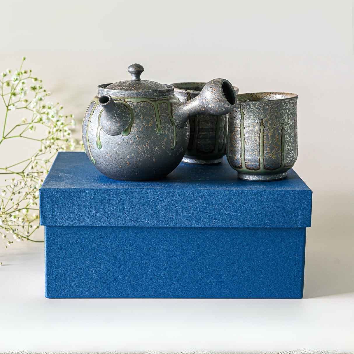 Japanese Kyusu Set - Teapot with Filters (230ml) and two cups on a blue box, paired with delicate white flowers—a stunning showcase of Japanese craftsmanship.