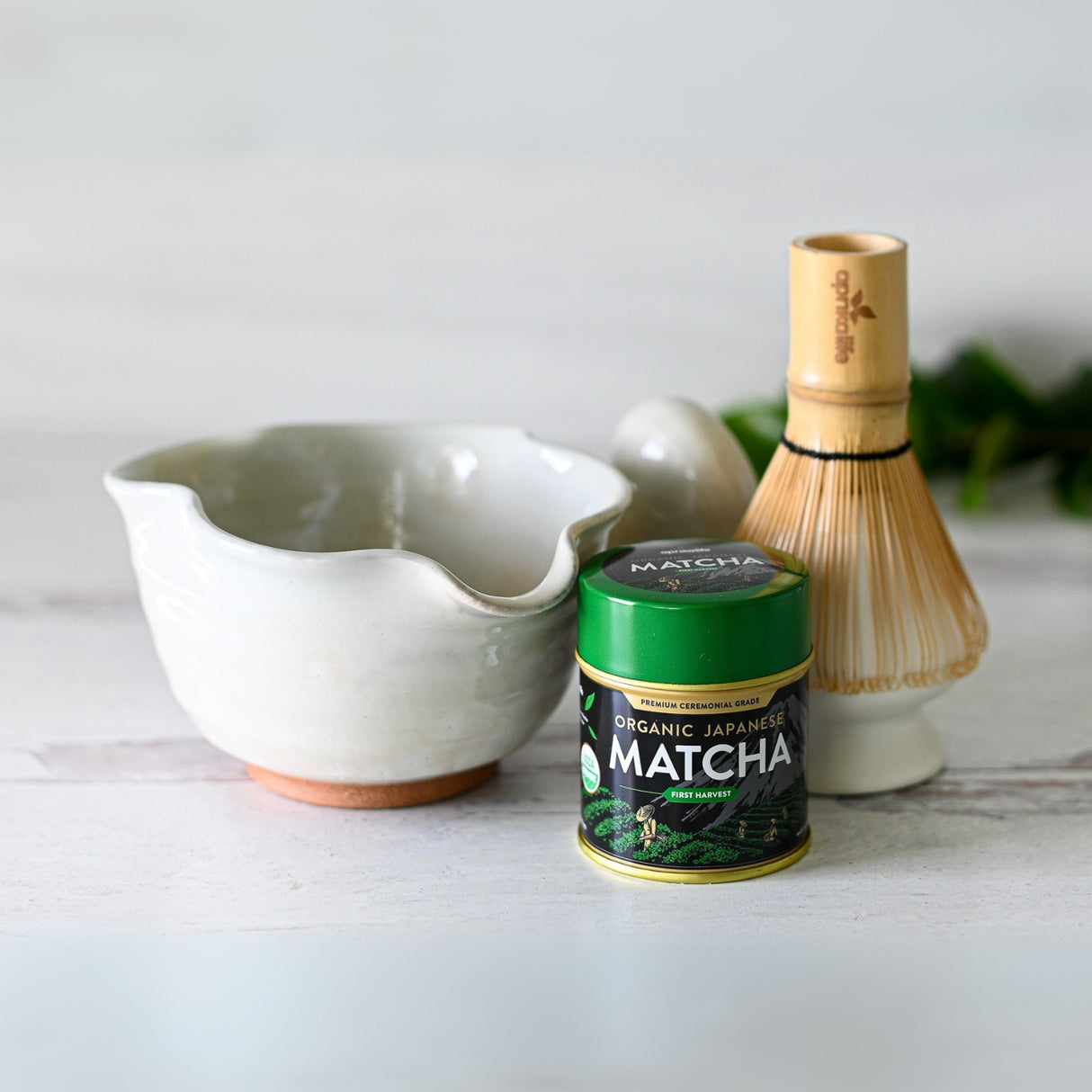 White Wavy Ceramic Matcha Bowl, Bamboo Matcha Whisk, Whisk Holder, and Organic Japanese Matcha Set on a white surface.