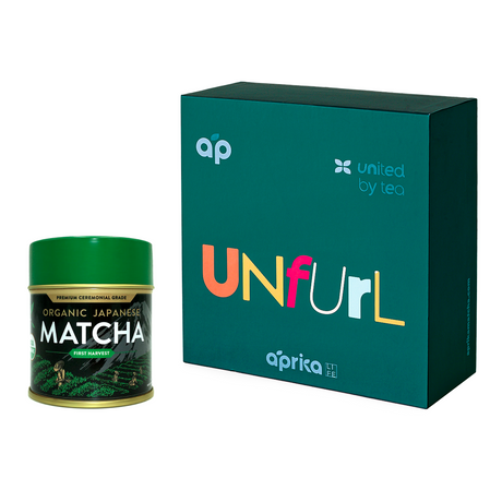 A Ceremonial Matcha Starter Kit - Blue tin, ideal for Japanese tea ceremonies, sits next to a dark teal Unfurl gift box with colorful lettering.