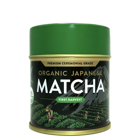 Green tin of Organic Japanese Ceremonial Grade Matcha Green Tea Powder featuring mountain and field illustrations on the label.