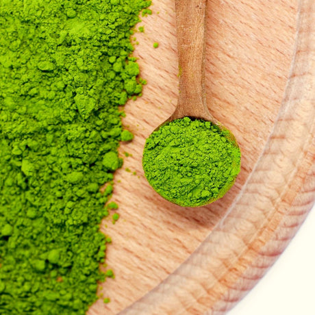 FREE Japanese Matcha Green Tea Powder (3.5 oz/100g) displayed on a wooden board, with a small wooden spoon filled with vibrant premium matcha.