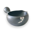 The Black Flowers Ceramic Matcha Bowl with Spout, adorned with floral designs on a black background and featuring a side handle, makes an ideal housewarming gift for admirers of the Japanese tea ceremony.