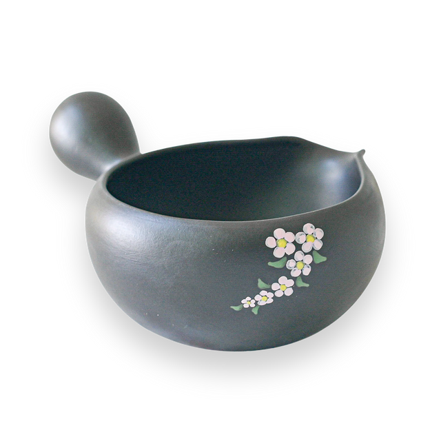 The Black Flowers Ceramic Matcha Bowl with Spout, adorned with floral designs on a black background and featuring a side handle, makes an ideal housewarming gift for admirers of the Japanese tea ceremony.