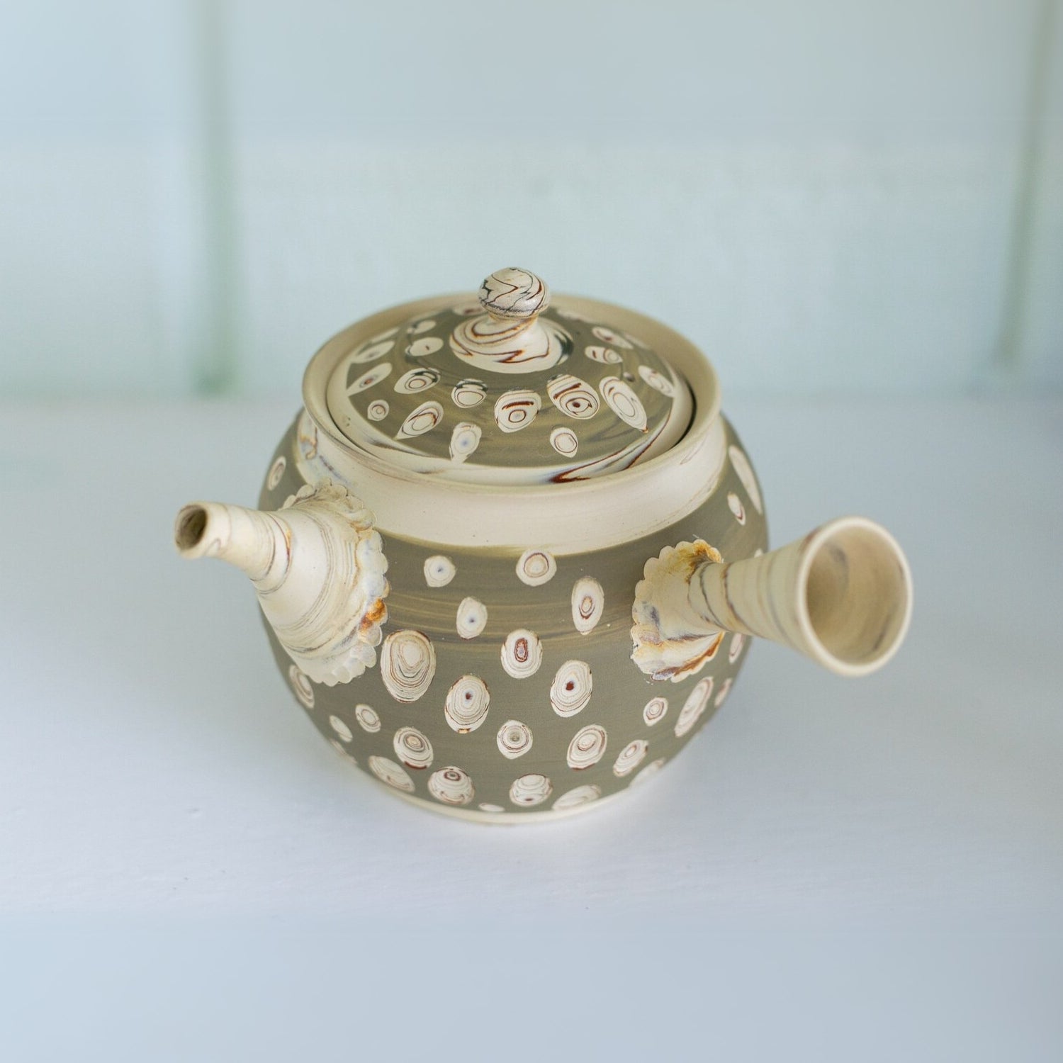 The Japanese Kyusu Set includes a teapot with filters (370ml) and two cups, crafted from Tokoname clay in beige, featuring circular patterns, a lid, and an elegantly angled spout, perfect for serving green tea.