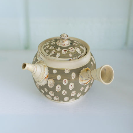 The Japanese Kyusu Set includes a teapot with filters (370ml) and two cups, crafted from Tokoname clay in beige, featuring circular patterns, a lid, and an elegantly angled spout, perfect for serving green tea.