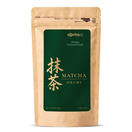 A stand-up pouch of Aprika Matcha Orumi premium ceremonial grade matcha tea, featuring a natural kraft paper design with a large dark green label and gold lettering.