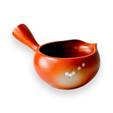 The Red Flowers Ceramic Matcha Bowl with Spout, featuring floral designs on a black background and a small handle, makes an elegant housewarming gift inspired by traditional Japanese tea ceremonies.