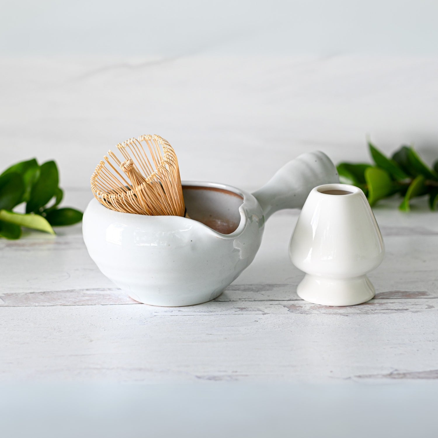The Gray Spouted Ceramic Matcha Bowl with Textured Handle, along with the Bamboo Matcha Whisk and Whisk Holder, is set against a light background, highlighting the elegance of Japanese pottery.