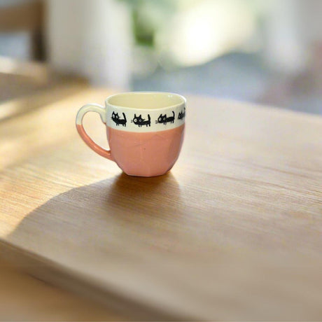 The Handmade Pink Ceramic Tea or Coffee Mug with Black Cats Print from Japan (8oz/250ml) adds charm to your morning as it sits on a sunlit wooden table.